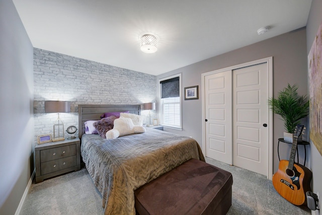 carpeted bedroom with a closet and brick wall