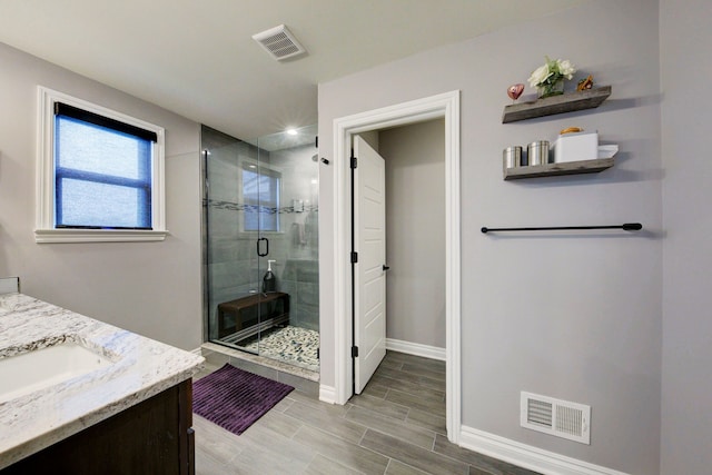 bathroom with visible vents, a shower stall, vanity, and baseboards