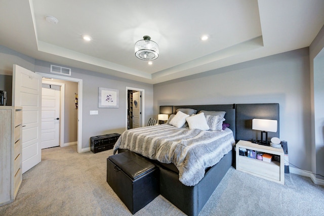 bedroom featuring a tray ceiling, visible vents, baseboards, light colored carpet, and a spacious closet
