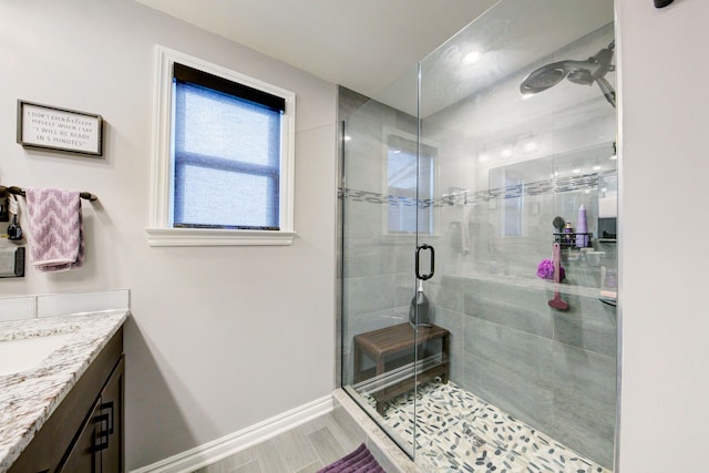 full bath with a stall shower, vanity, and baseboards