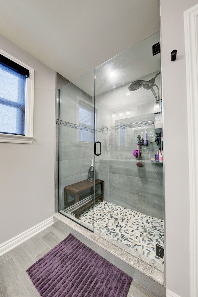 bathroom featuring wood finished floors, a shower stall, and baseboards