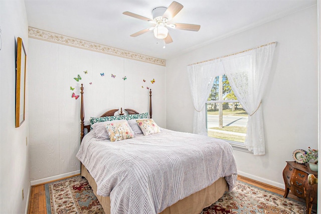 bedroom featuring a ceiling fan, wood finished floors, and baseboards