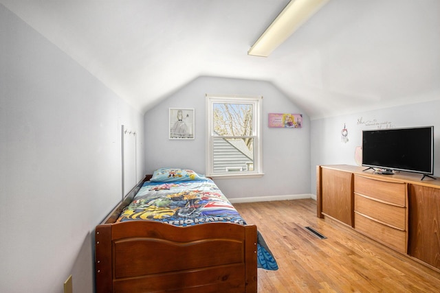 bedroom featuring visible vents, light wood-type flooring, baseboards, and vaulted ceiling