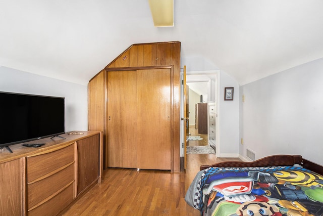 bedroom featuring visible vents, light wood-style floors, and vaulted ceiling