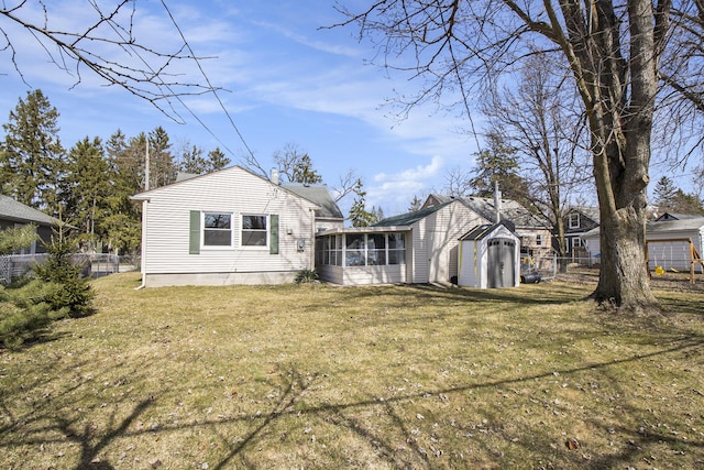 back of house with a storage shed, fence, a yard, and a sunroom