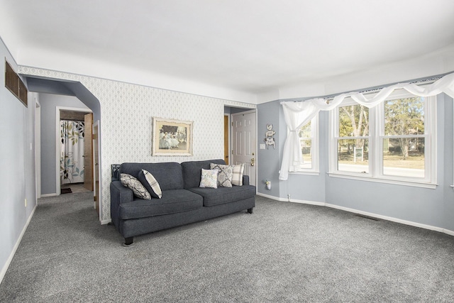 carpeted living room with wallpapered walls, visible vents, baseboards, and arched walkways