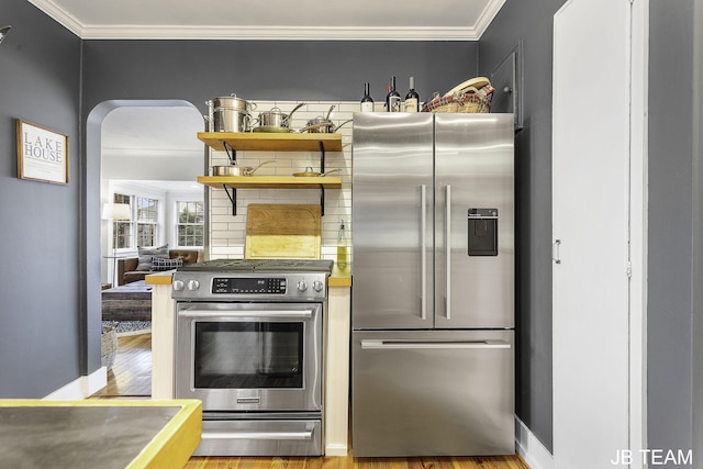 1200 Beach Dr, Holland, MI 49423 - kitchen featuring stainless steel appliances, ornamental molding, wood finished floors, arched walkways, and decorative backsplash