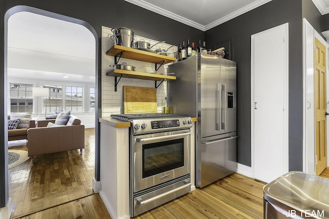 1200 Beach Dr, Holland, MI 49423 - kitchen with appliances with stainless steel finishes, light wood-style floors, crown molding, tasteful backsplash, and baseboards