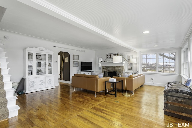 1200 Beach Dr, Holland, MI 49423 - living area featuring arched walkways, a stone fireplace, hardwood / wood-style flooring, baseboards, and crown molding