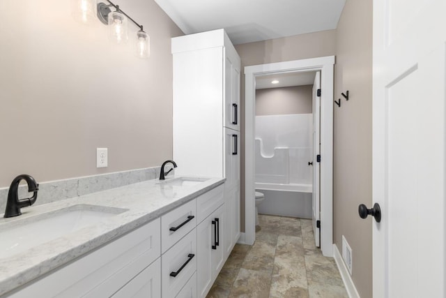 144 9 Mile Rd NW, Comstock Park, MI 49321 - bathroom featuring baseboards, stone finish flooring, double vanity, and toilet