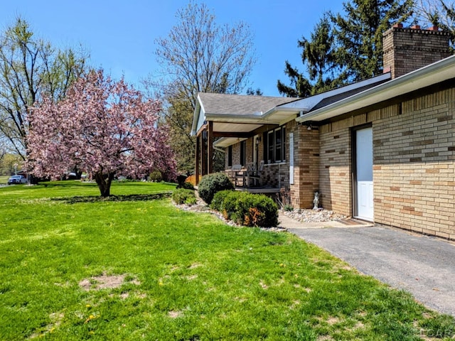 13936 Allen Rd, Clinton, MI 49236 - view of property exterior featuring a lawn, covered porch, a chimney, and brick siding