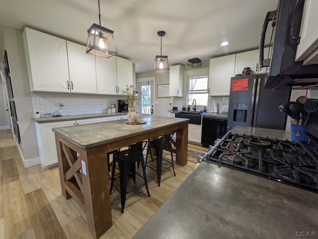 13936 Allen Rd, Clinton, MI 49236 - kitchen featuring tasteful backsplash, light wood-style floors, white cabinets, black appliances, and a sink