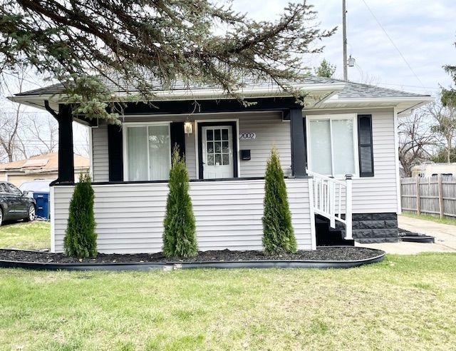 bungalow-style home featuring a front yard, a porch, and fence