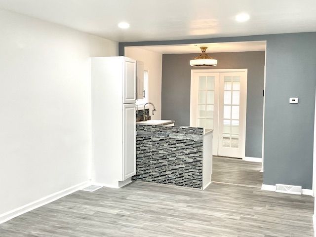 kitchen with light wood-style floors, baseboards, white cabinetry, and recessed lighting