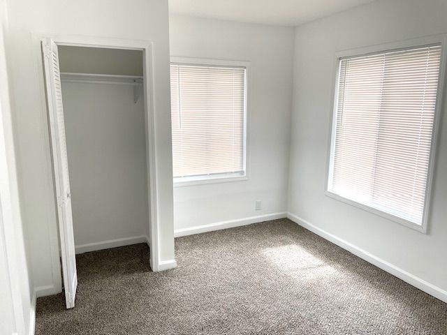 unfurnished bedroom featuring a closet, baseboards, and carpet flooring