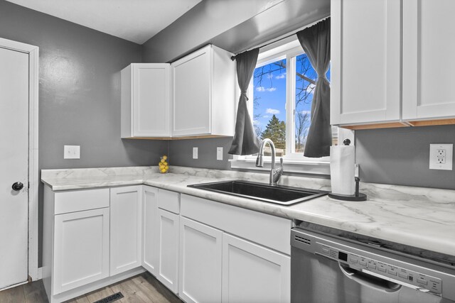 5278 W Mobile Trl, Traverse City, MI 49685 - kitchen featuring wood finished floors, light stone countertops, a sink, white cabinets, and stainless steel dishwasher