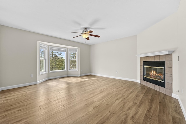 unfurnished living room with a fireplace, baseboards, a ceiling fan, and wood finished floors