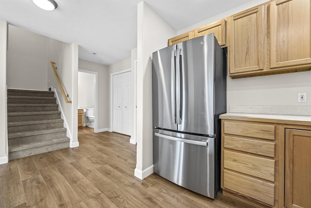 kitchen with baseboards, light brown cabinetry, light countertops, light wood-style flooring, and freestanding refrigerator