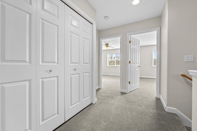 corridor featuring baseboards and light carpet