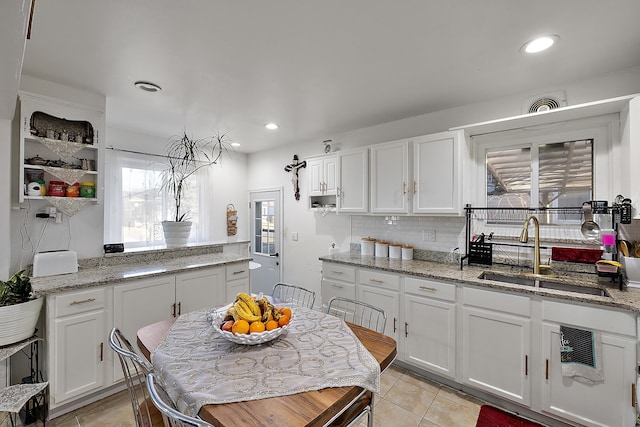 kitchen featuring a sink, decorative backsplash, light tile patterned flooring, and white cabinetry