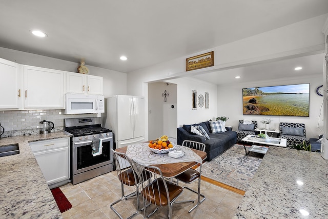 kitchen with light stone countertops, open floor plan, decorative backsplash, white cabinets, and white appliances