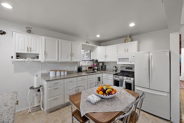 kitchen with tasteful backsplash, recessed lighting, white appliances, white cabinetry, and a sink