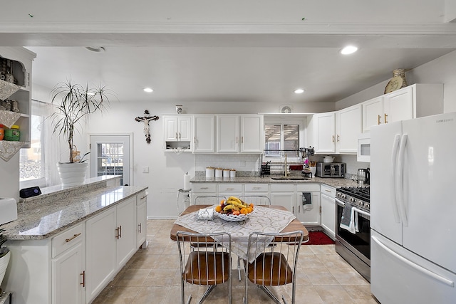 kitchen featuring recessed lighting, white appliances, white cabinetry, and a sink