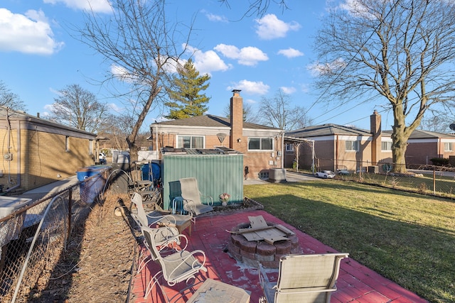 view of yard with a shed, an outdoor fire pit, central AC, a fenced backyard, and an outbuilding
