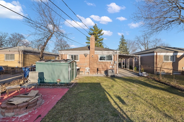 back of property with a fenced backyard, central AC, a chimney, a lawn, and brick siding