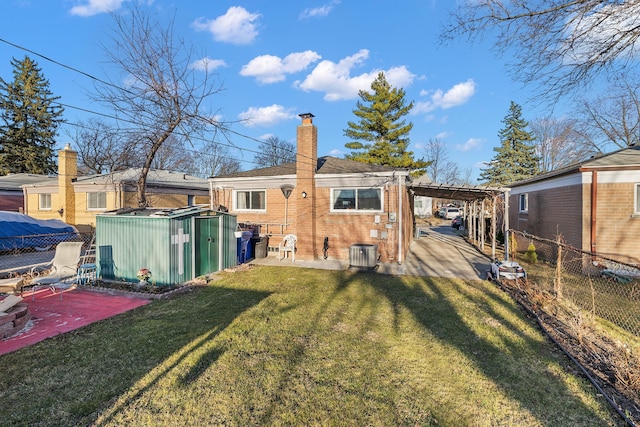 rear view of property featuring an outbuilding, fence, a storage unit, a patio area, and a lawn