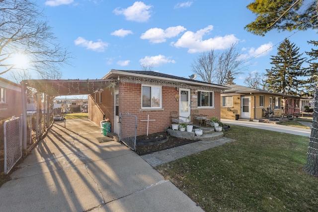view of front of house featuring brick siding, an attached carport, fence, concrete driveway, and a front yard