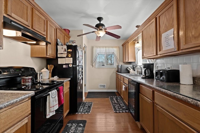 kitchen featuring under cabinet range hood, black appliances, brown cabinetry, and a sink
