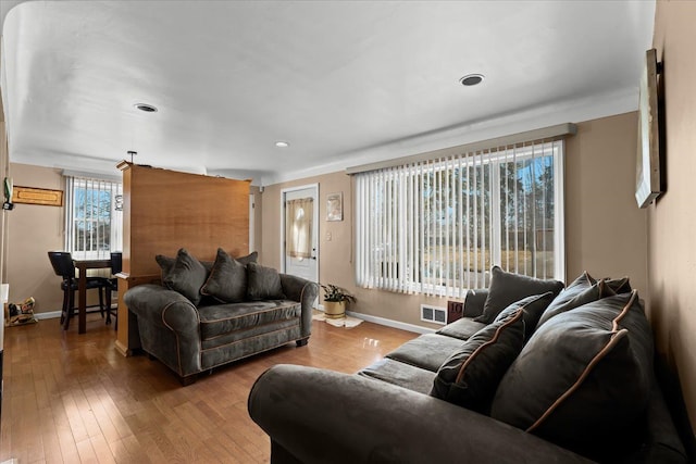 living area with visible vents, wood-type flooring, and baseboards