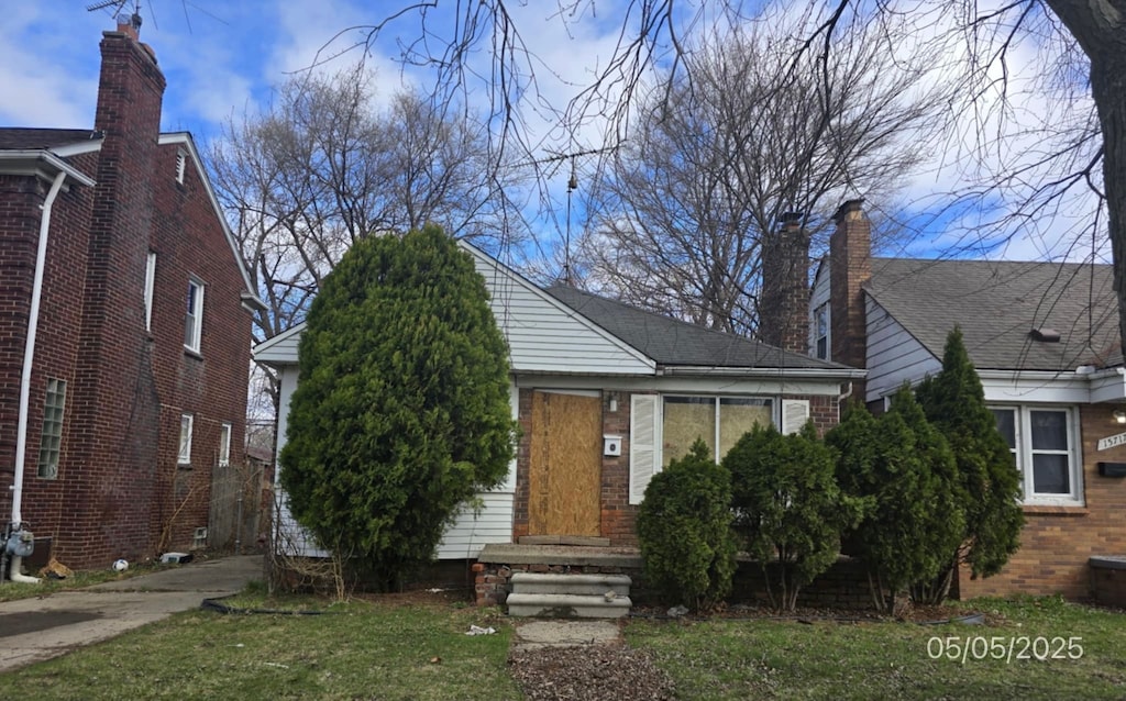 15709 Carlisle St, Detroit, MI 48205 - view of front facade with brick siding, driveway, and a front yard