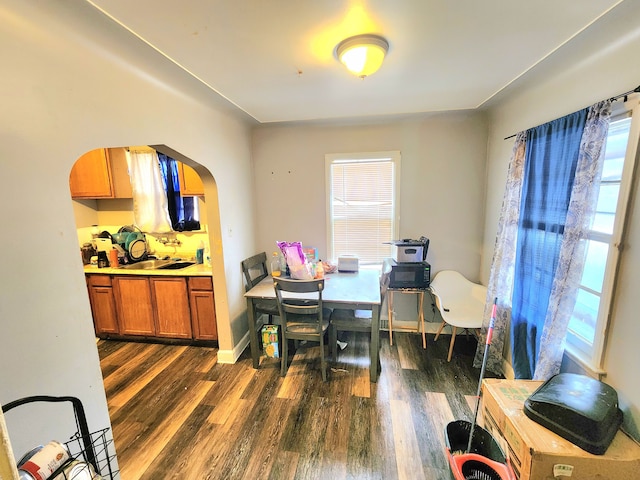 dining area with baseboards, arched walkways, and dark wood-style flooring