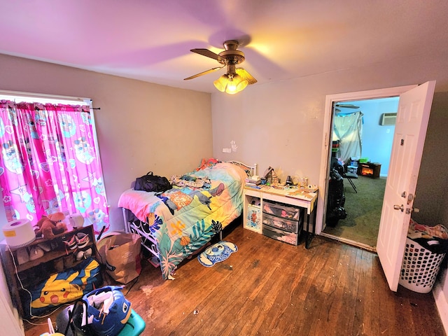 bedroom featuring ceiling fan, wood finished floors, and a wall unit AC