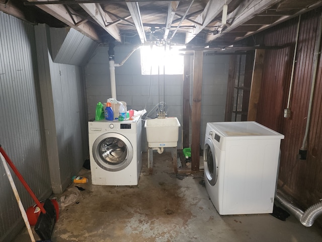 unfinished below grade area with concrete block wall, a sink, and washer and clothes dryer