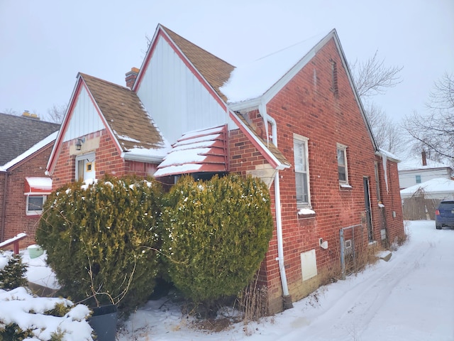 snow covered property featuring brick siding