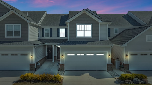 view of front of house with driveway, a garage, brick siding, and roof with shingles