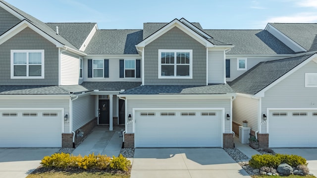 view of front of property featuring driveway, a shingled roof, a garage, and brick siding