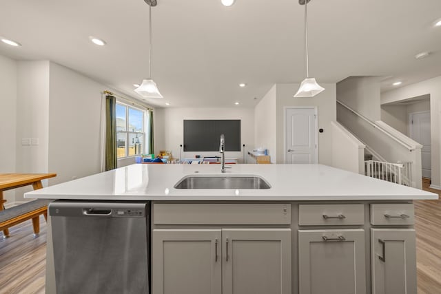 kitchen with dishwasher, a sink, gray cabinetry, and light wood finished floors