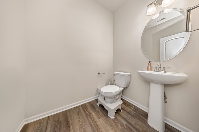 bathroom with baseboards, visible vents, toilet, and wood finished floors
