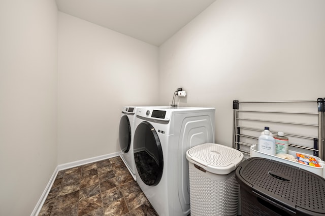 laundry area with stone finish floor, baseboards, washer and dryer, and laundry area