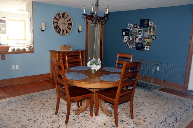 dining space with baseboards, wood finished floors, and an inviting chandelier