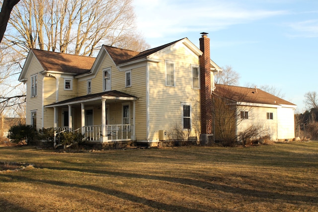 exterior space featuring covered porch, central air condition unit, a yard, and a chimney