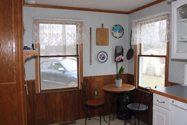 dining space with wallpapered walls, a wainscoted wall, and ornamental molding