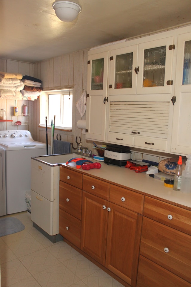 kitchen featuring glass insert cabinets, light countertops, brown cabinetry, and washer and clothes dryer