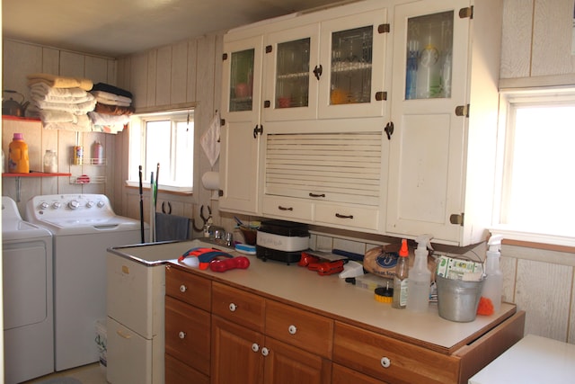washroom with cabinet space, wood walls, and washer and dryer