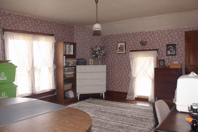 dining space with wallpapered walls, baseboards, and wood finished floors