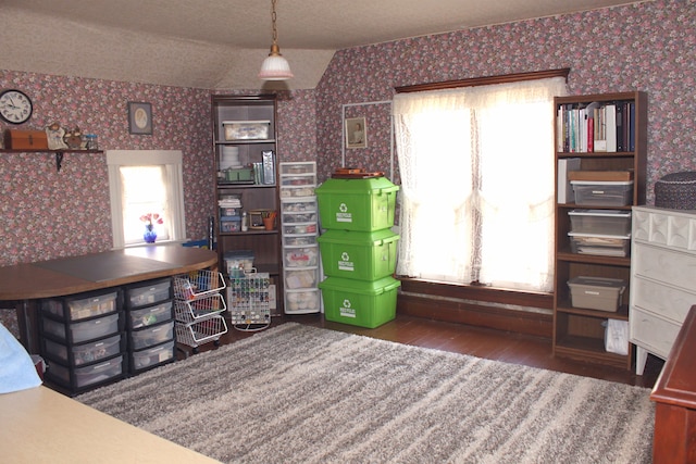 unfurnished office featuring lofted ceiling, a textured ceiling, wallpapered walls, and wood finished floors